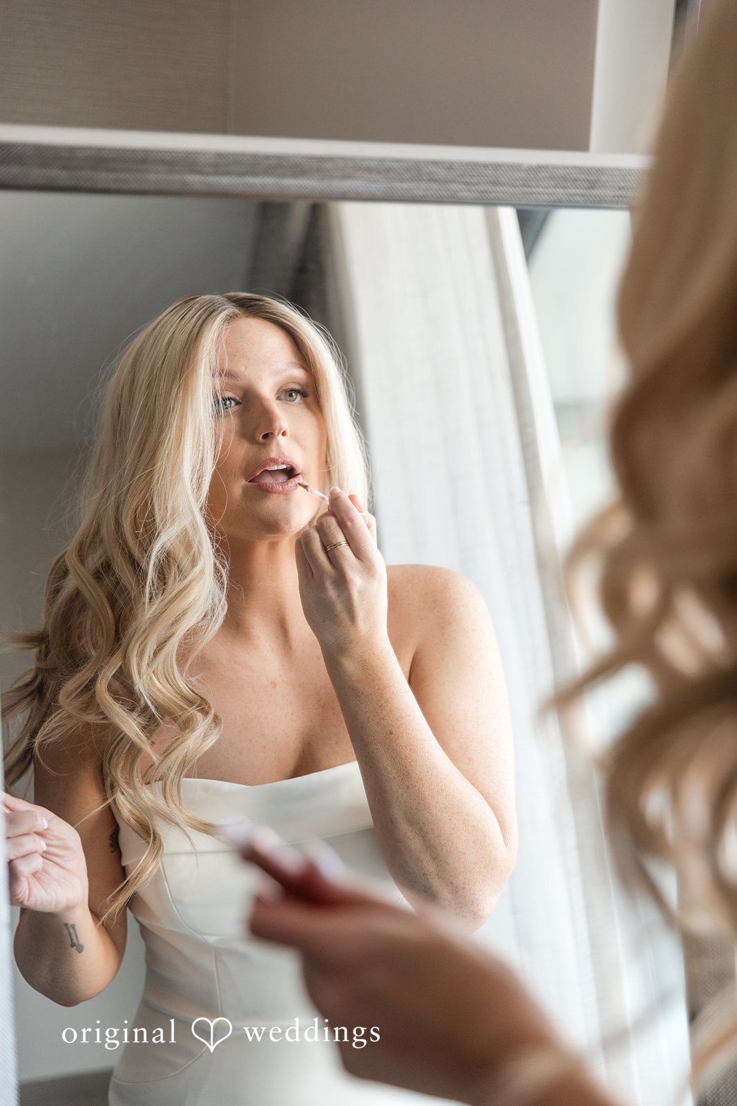 Bride looking into a mirror while getting ready.