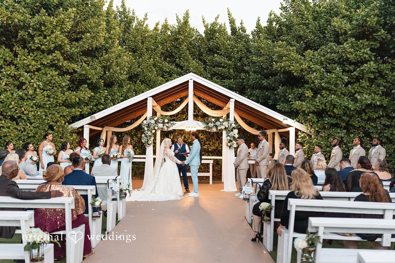 Couple standing before the priest looking at each other at Lovely Barn