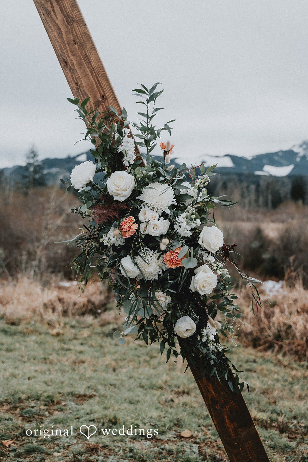 Kelsey + Adam Floral arrangement on wooden arch in outdoor setting.