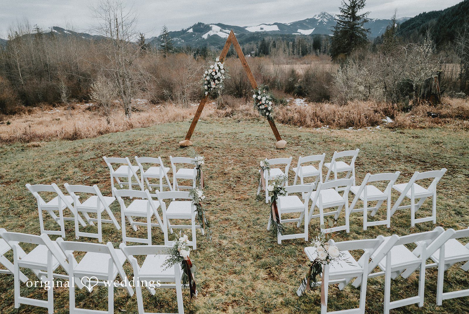 Kelsey + Adam Rows of white chairs arranged for outdoor wedding ceremony.