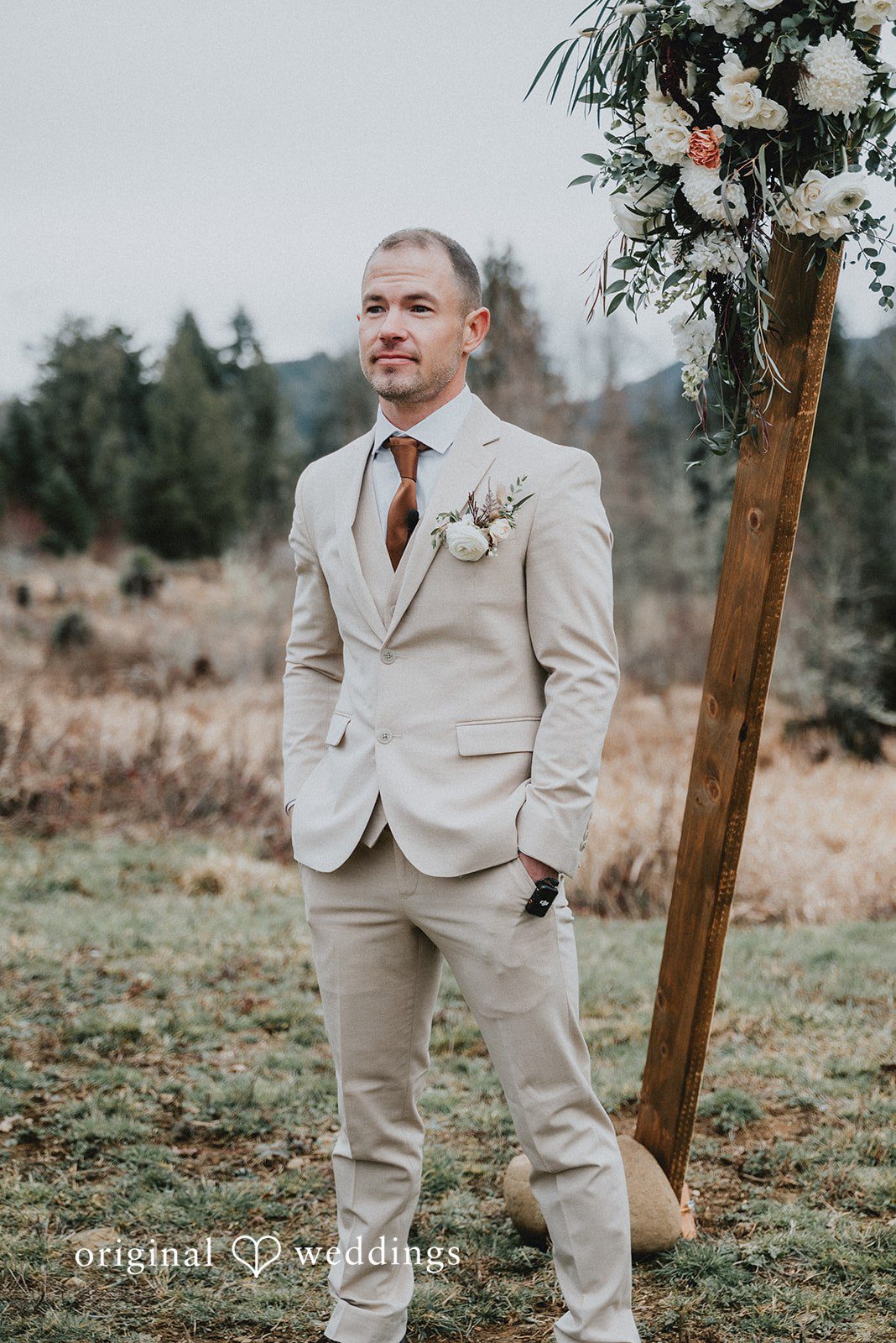 Kelsey + Adam Groom standing alone in a beige suit.