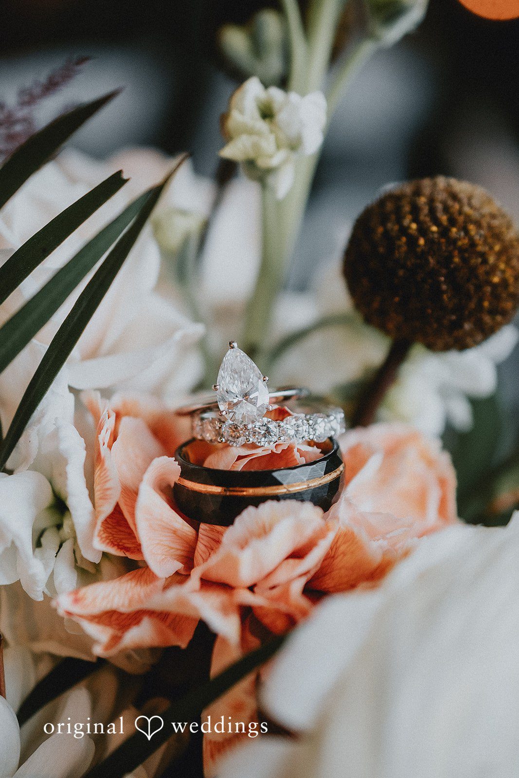 Kelsey + Adam Close-up of wedding rings on floral arrangement.