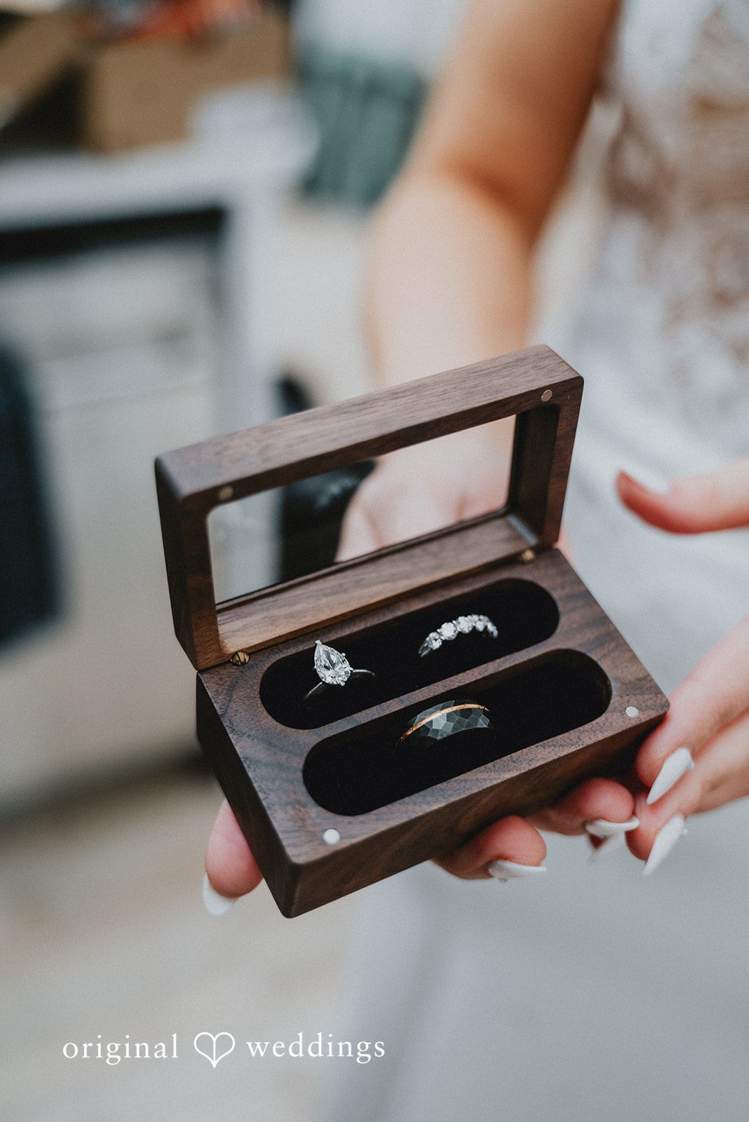 Kelsey + Adam Wedding rings in a box held by someone.