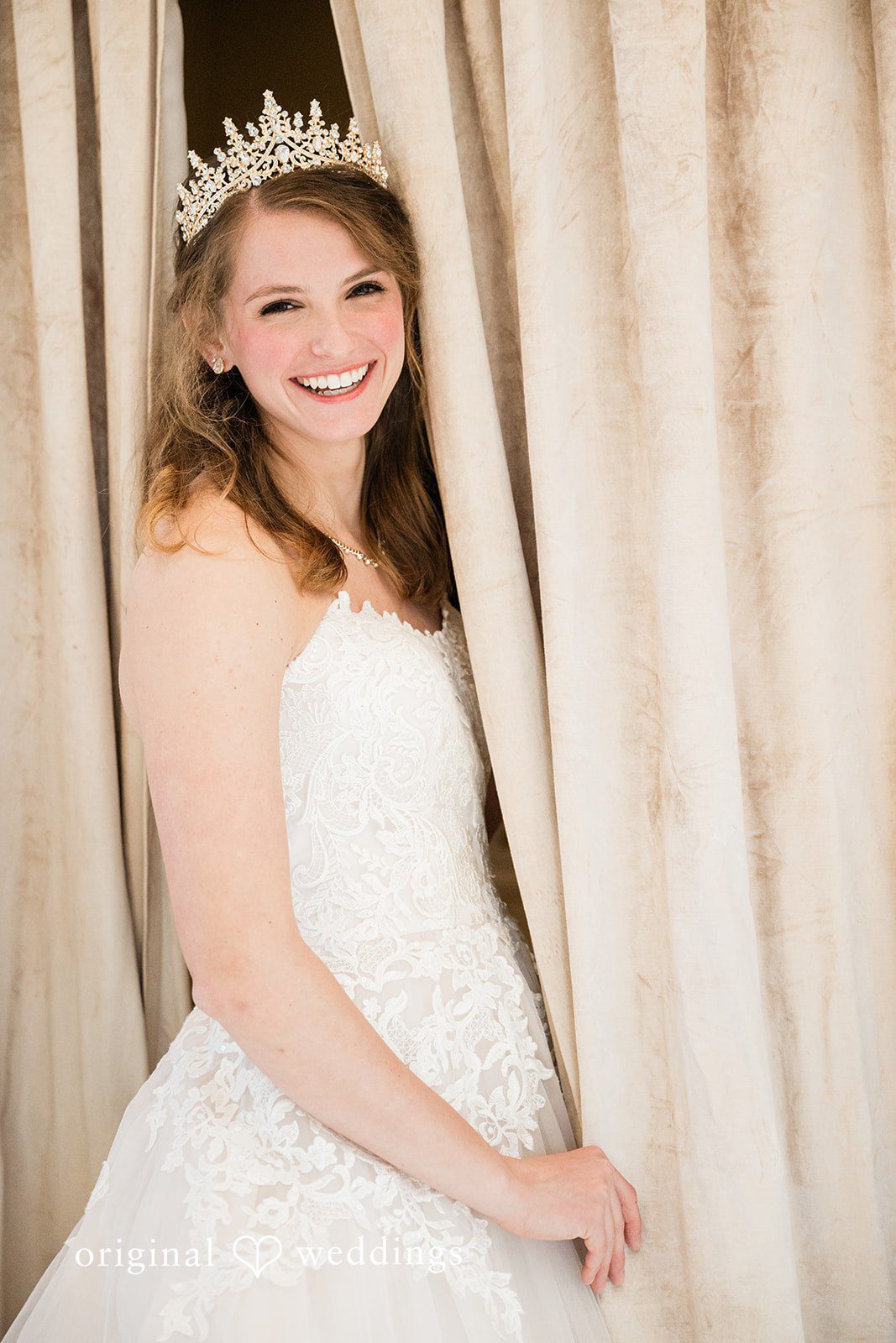 Celine + Cassin Smiling bride posing in a wedding dress near curtains.