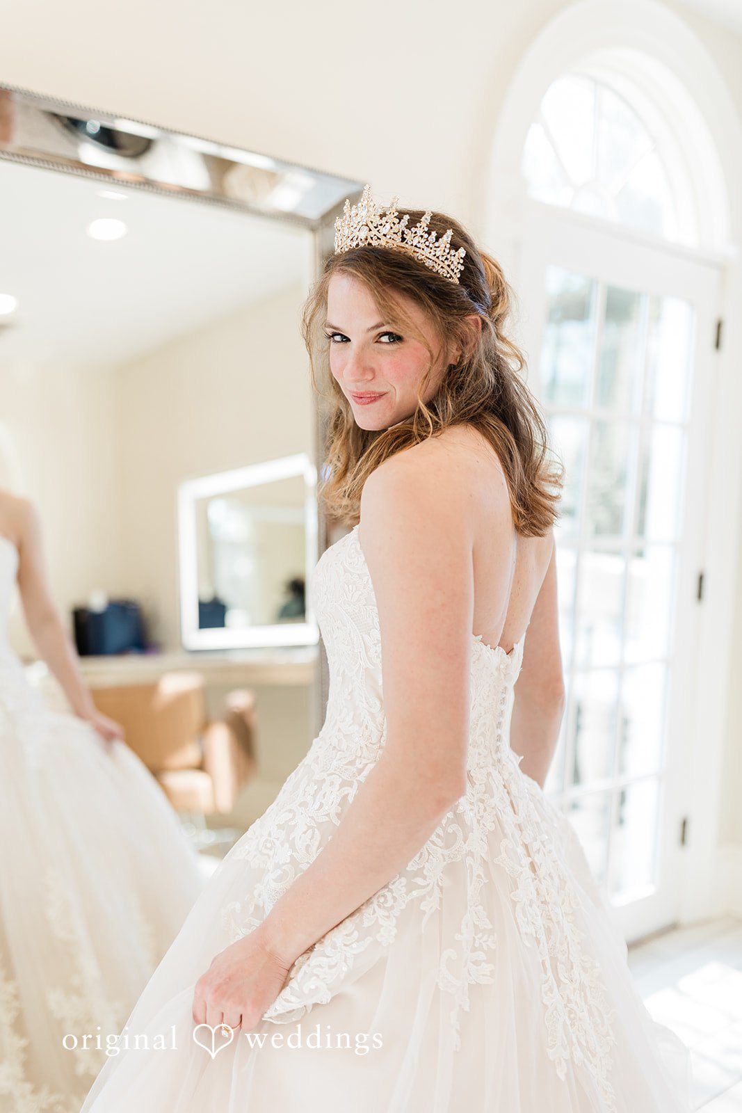 Celine + Cassin Bride in a white gown looking back over her shoulder in a bright room.