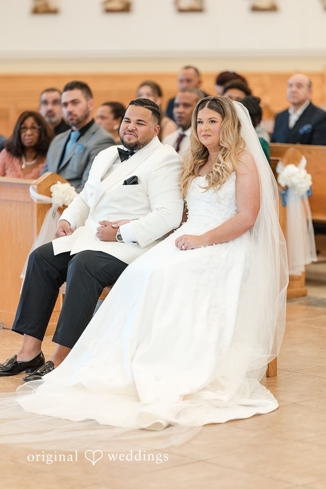A portrait of the couple seated in their church wedding ceremony