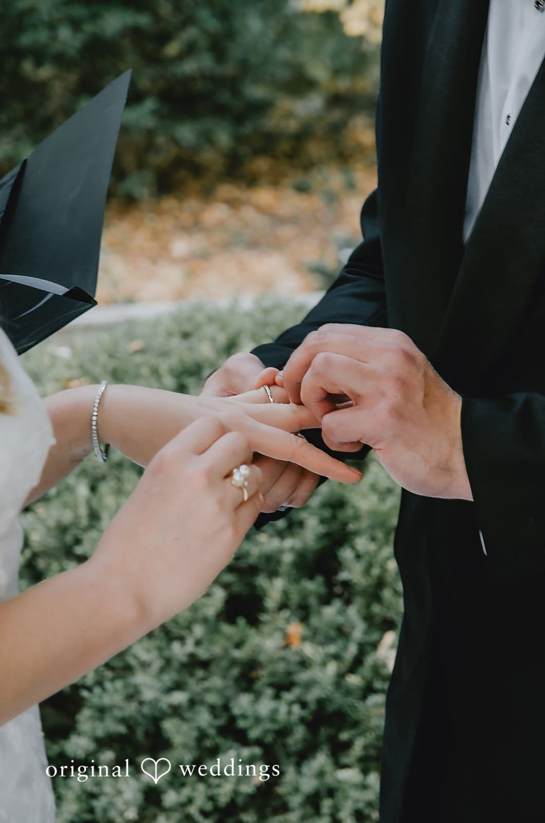 A close-up shot of the groom putting a ring on bride's finger at their Missouri wedding venue