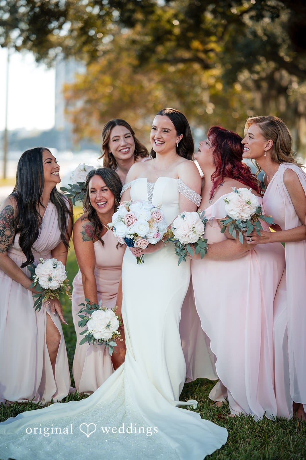 Bride posing with her bridesmaids in pink dresses holding their bouquets