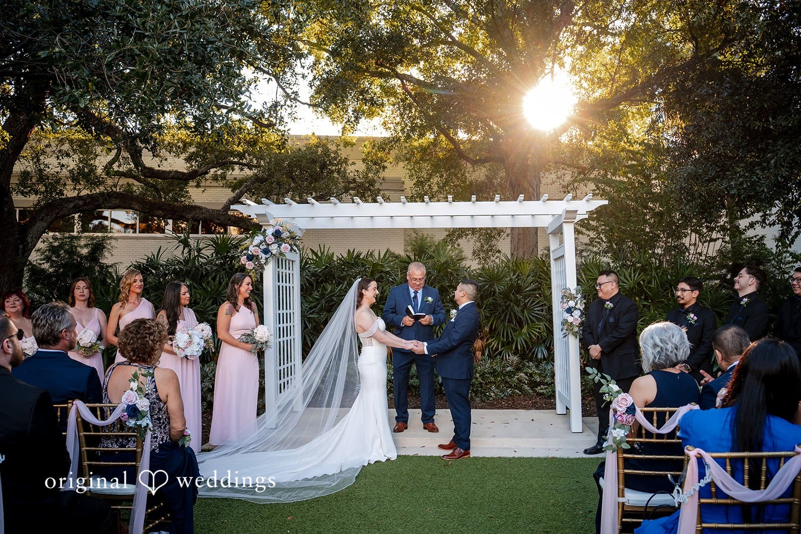 Bride and groom standing together beneath the white ceremony arbor