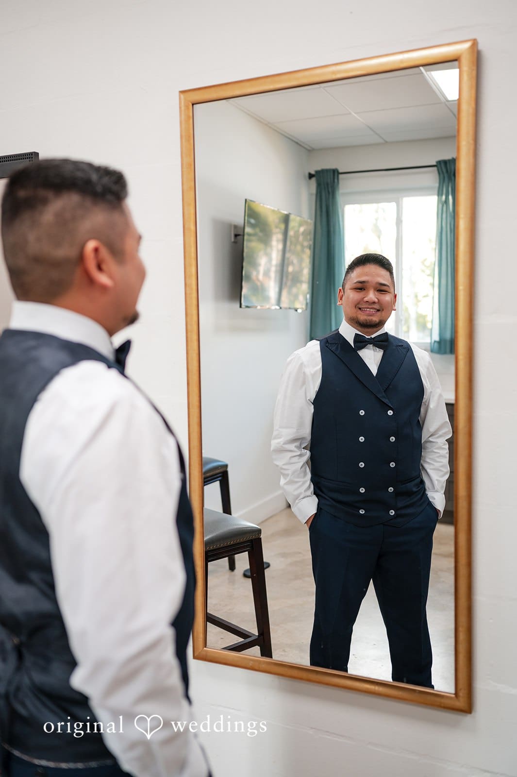 Groom getting ready in front of mirror before ceremony