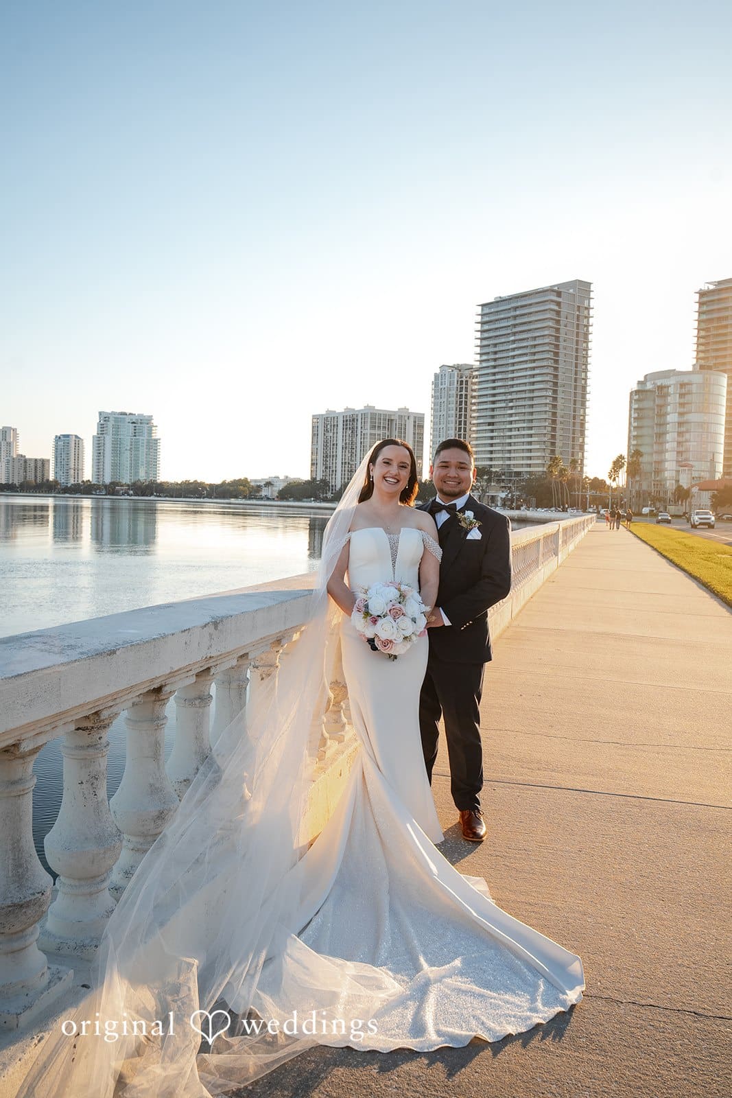 Bride posing by the waterfront promenade with her veil flowing in the breeze
