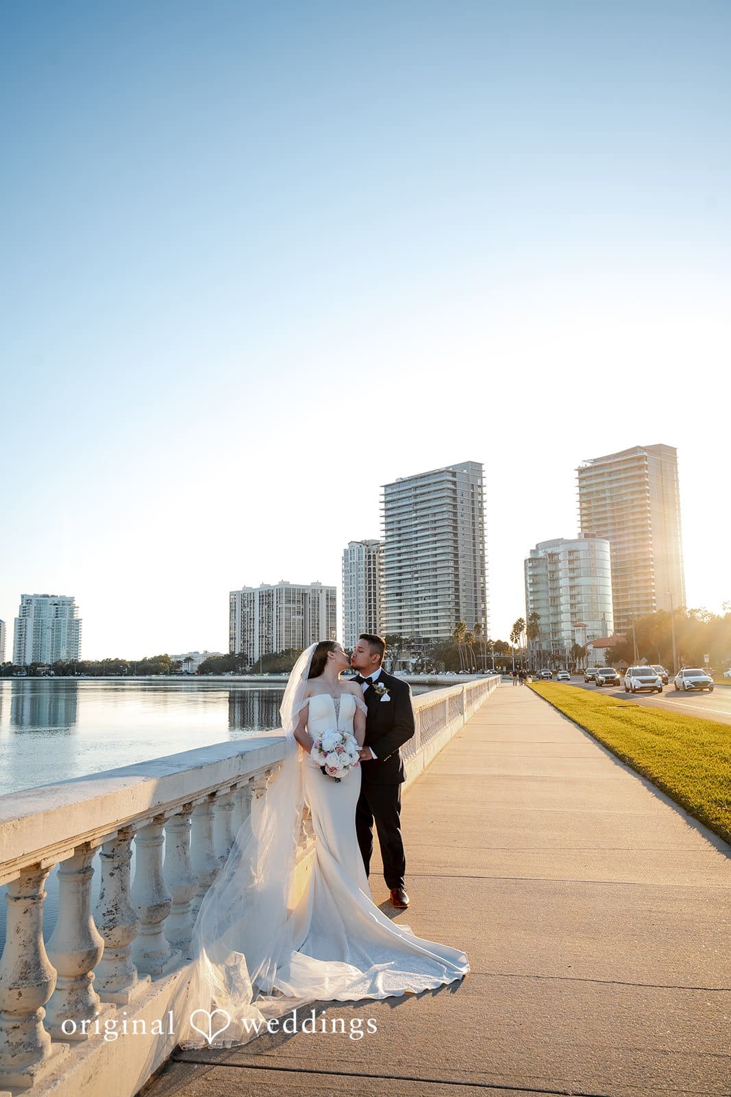 Bride and groom sharing a kiss by the waterfront railing with the Tampa skyline behind them