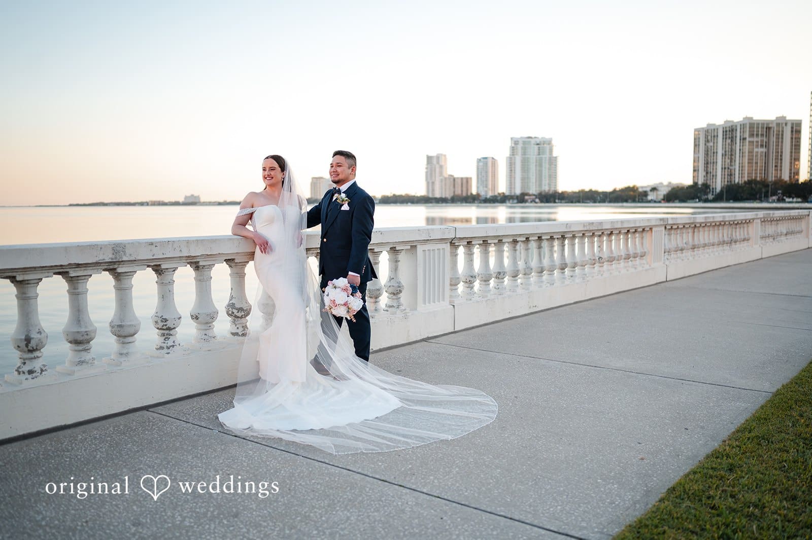 Bride and groom posing for portraits by the waterfront at Tampa Garden Club with views of the Tampa skyline