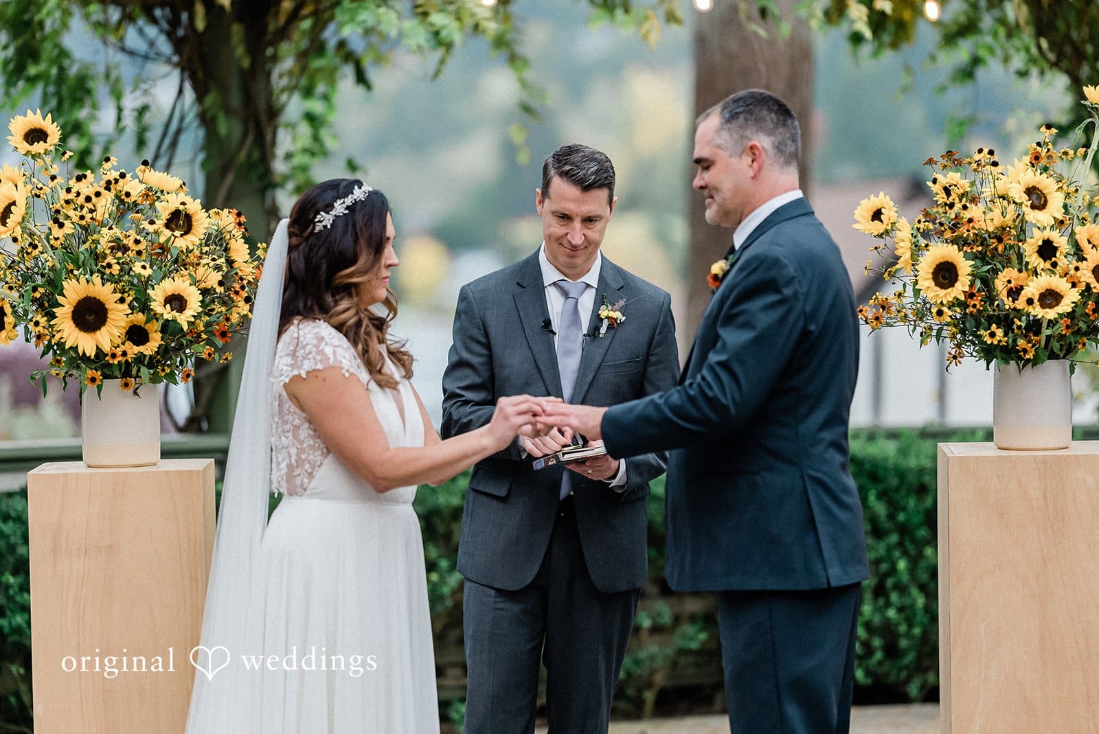 Bride and groom exchanging rings during outdoor wedding ceremony