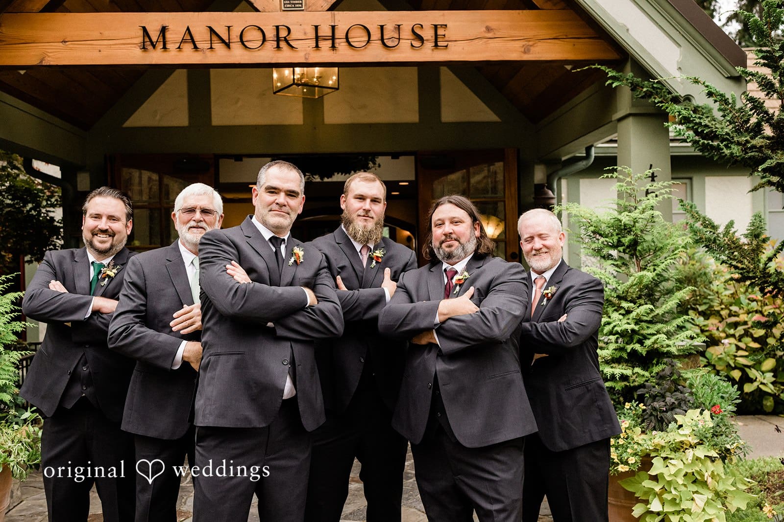 Groom standing with his groomsmen, all dressed in suits and smiling