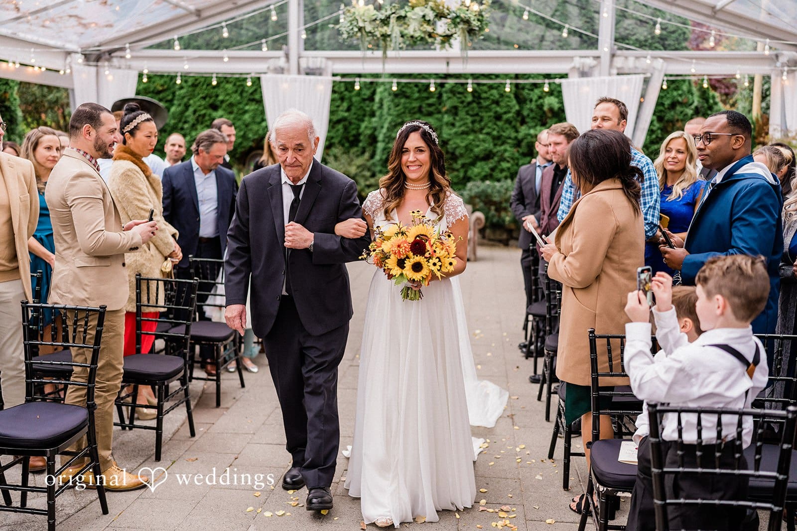 Bride walking arm-in-arm with her father, both smiling
