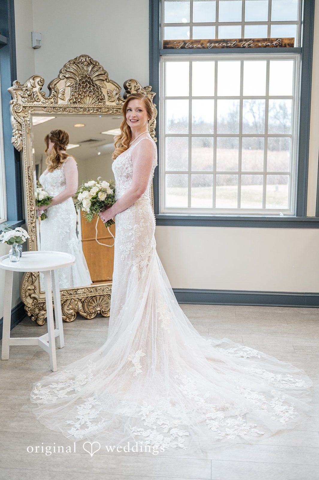 Caitlyn + Greg Bride standing near a window in a white wedding gown at The Osprey’s at Belmont Bay