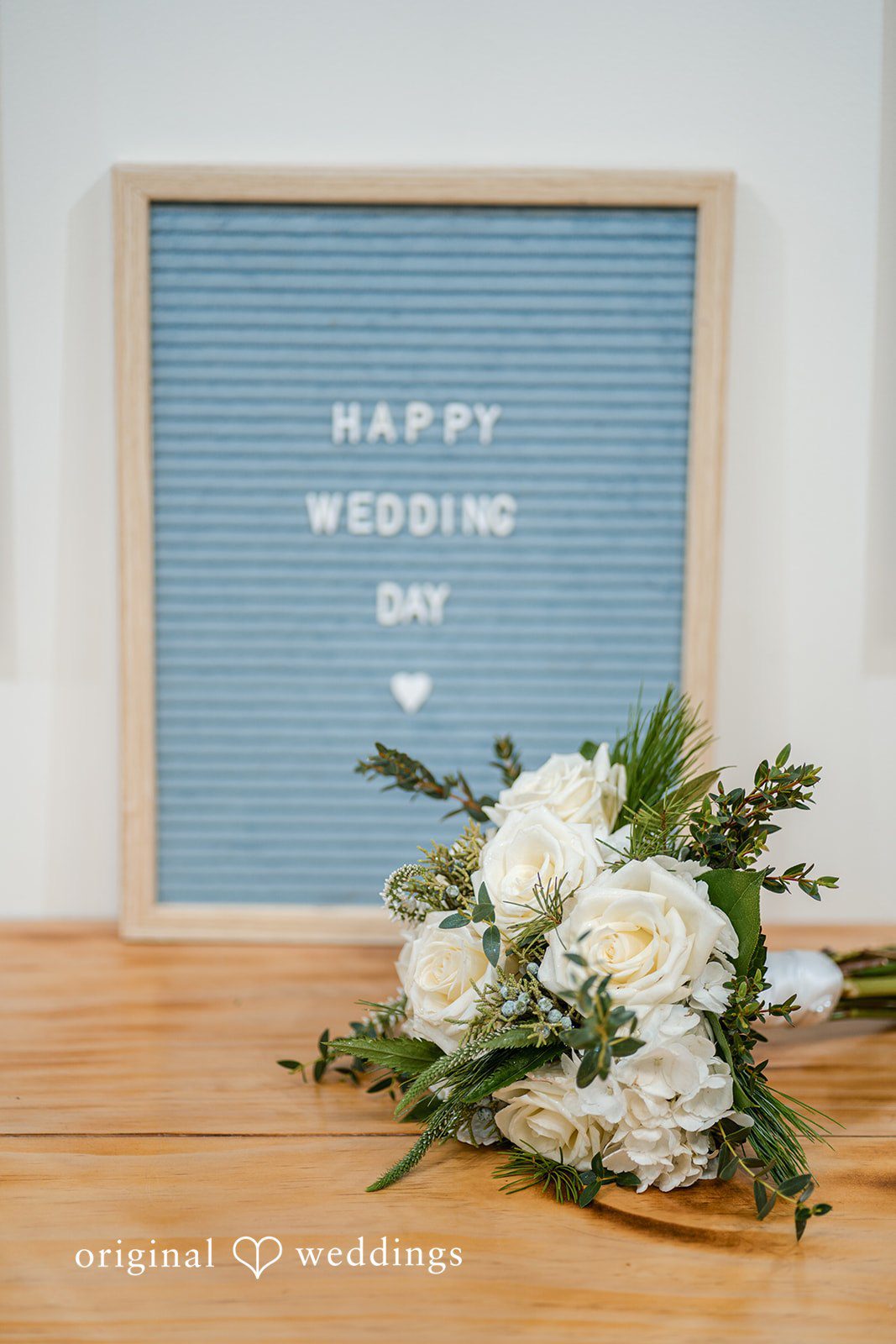Caitlyn + Greg Wedding sign board with floral arrangement on a wooden table