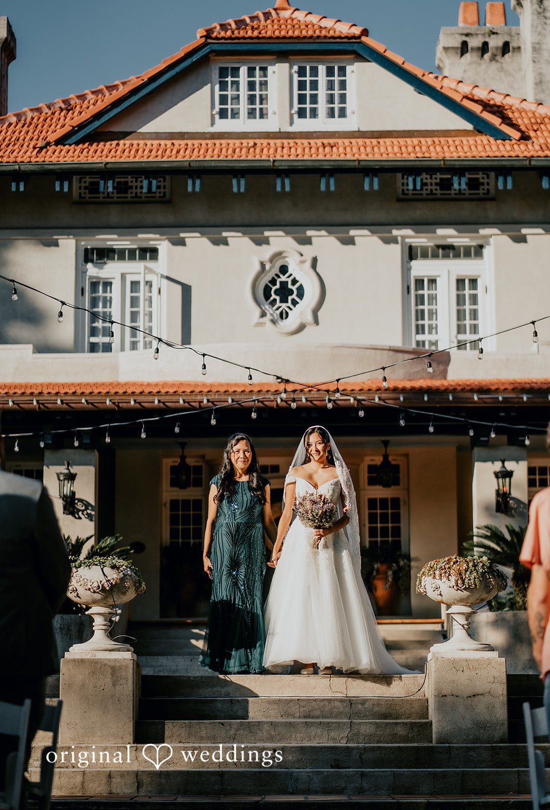 The couple stands in front of a charming wedding venue.