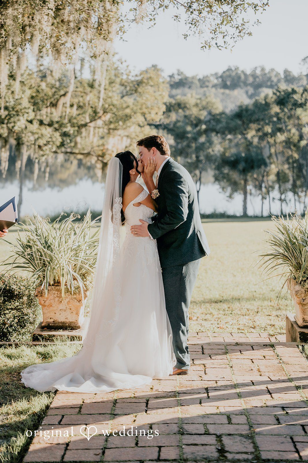 The couple shares a romantic kiss by the water.
