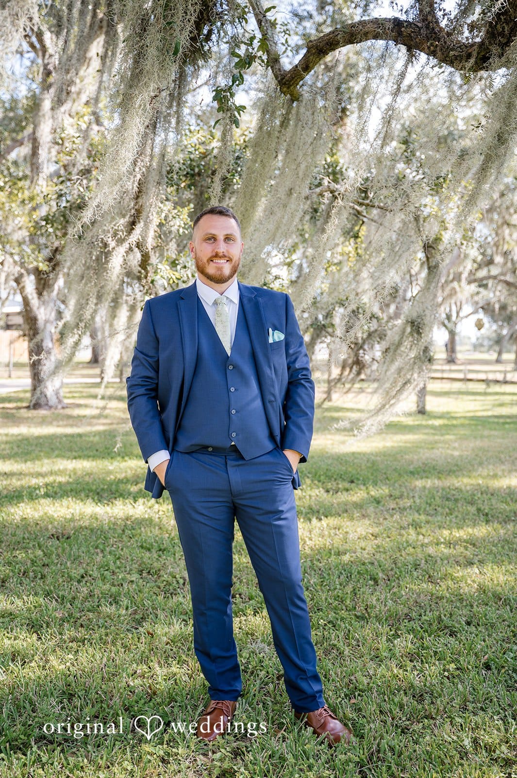 The groom poses alone outdoors for a stylish portrait.