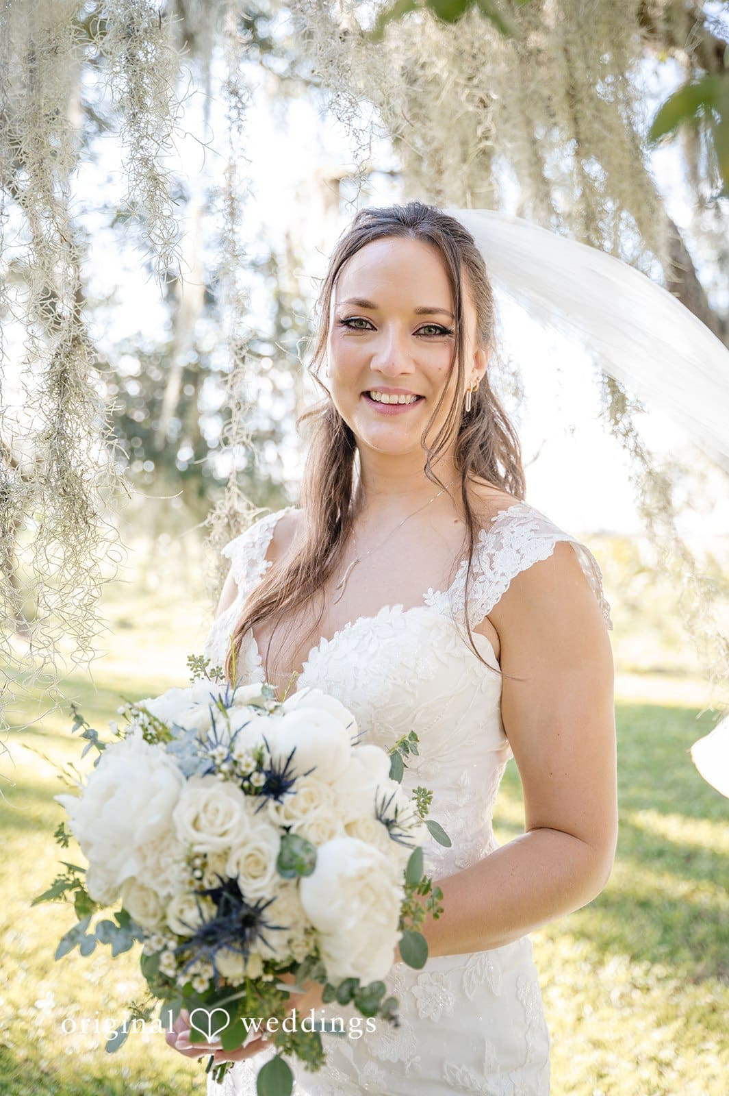 The bride smiles gracefully while holding her bouquet.