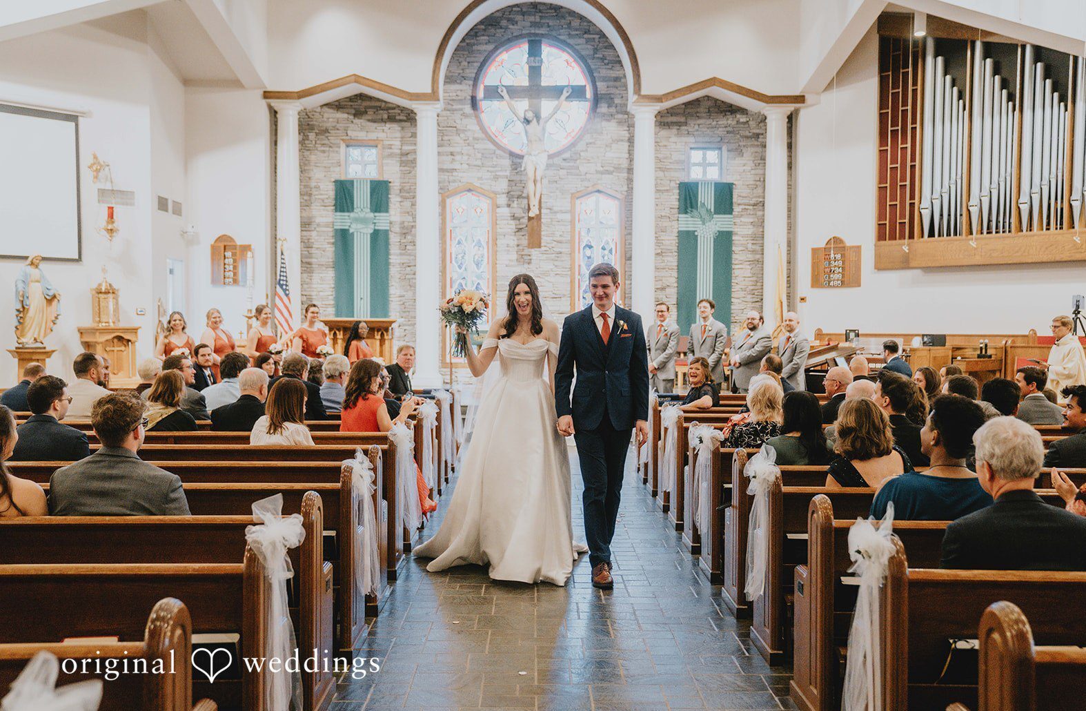 This church aisle recessional photo was captured by an Atlanta Wedding Photographer, showing the couple walking together after the ceremony inside a light-filled chapel.