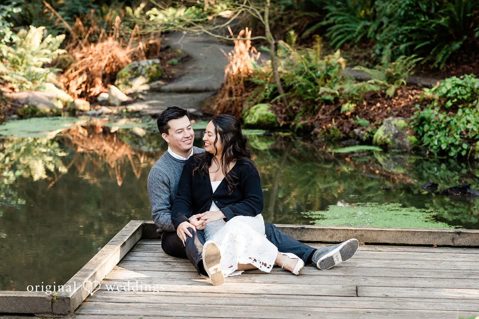 Romantic engagement photo of couple seated together on the ground at Washington Park Arboretum