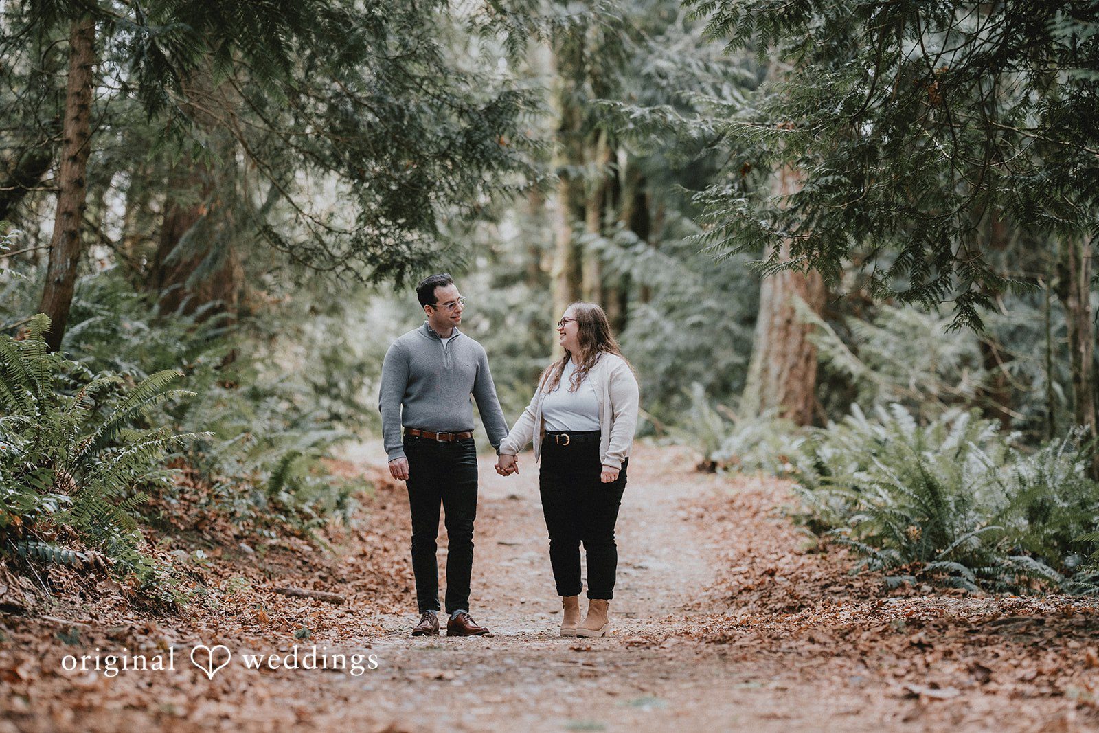 Couple walking side by side, holding hands and smiling at Coal Creek Natural Area.