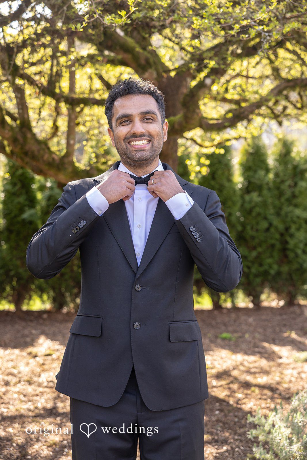 A portrait of the groom adjusting his tie