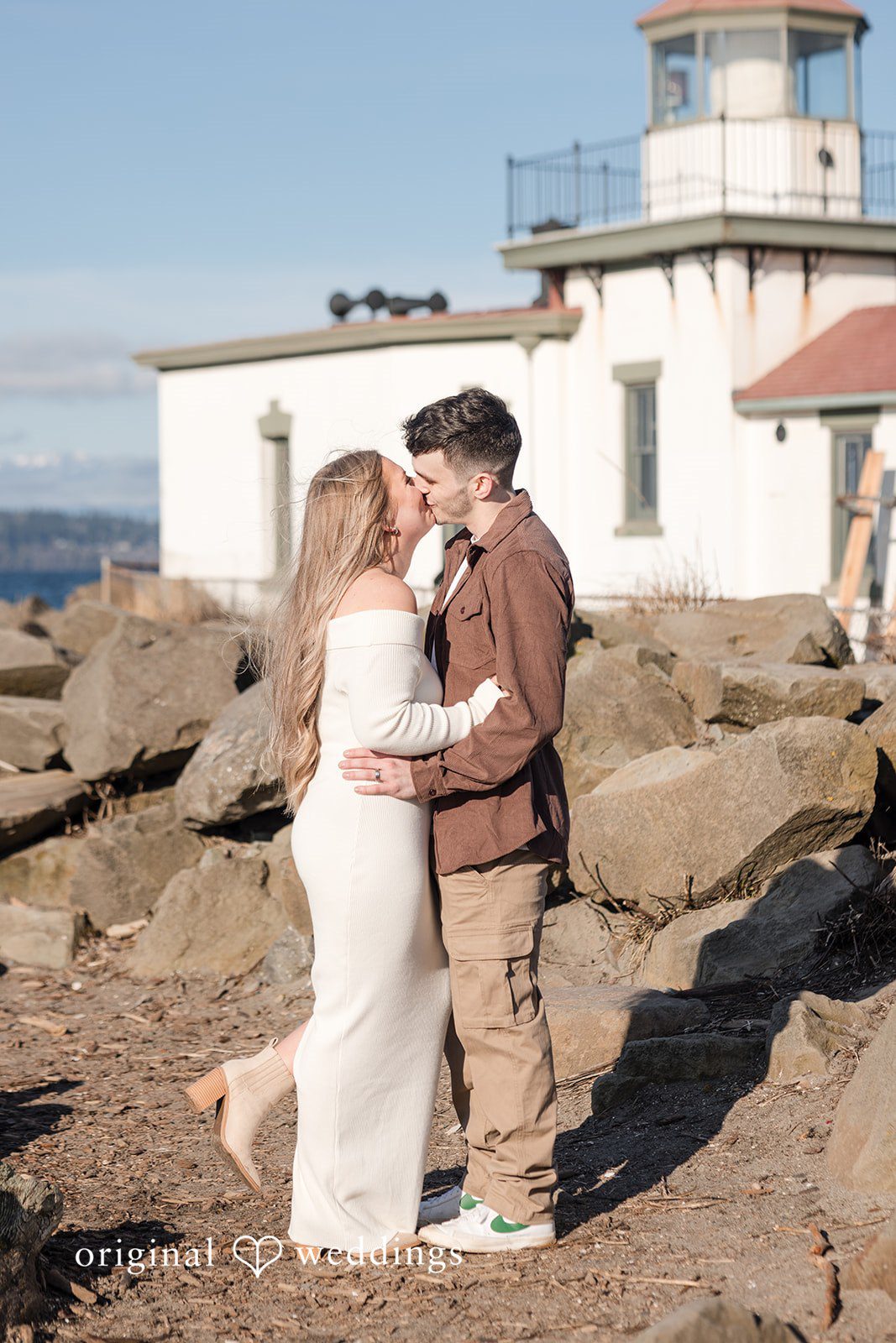 Couple embracing on rocky beach during Discovery Park engagement photography session