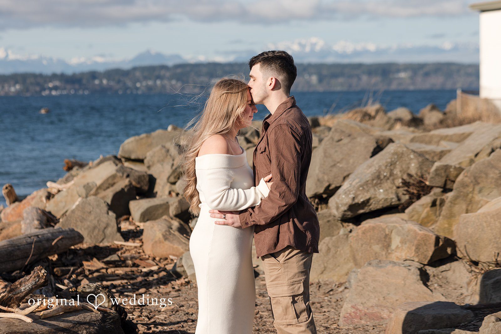 Couple embracing on rocky beach during Discovery Park engagement photography session