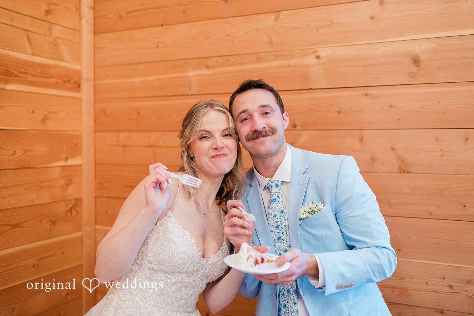 Aubrey + Casey The couple smiles while enjoying dessert together in a warm wooden setting.