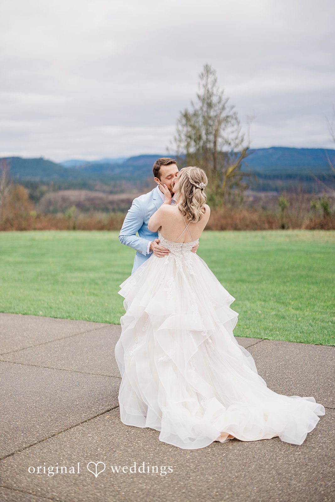 Aubrey + Casey The bride and groom embrace outdoors with a scenic landscape behind them.
