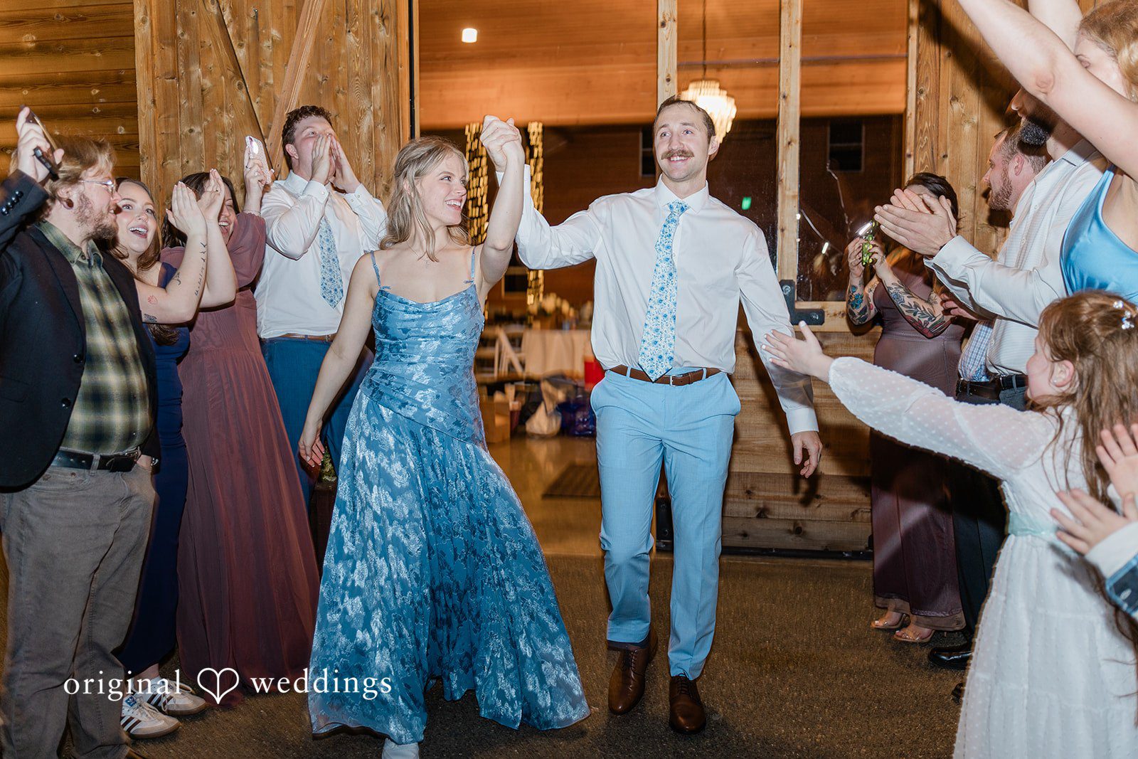Aubrey + Casey The bride and groom joyfully enter the reception while guests cheer and celebrate around them.