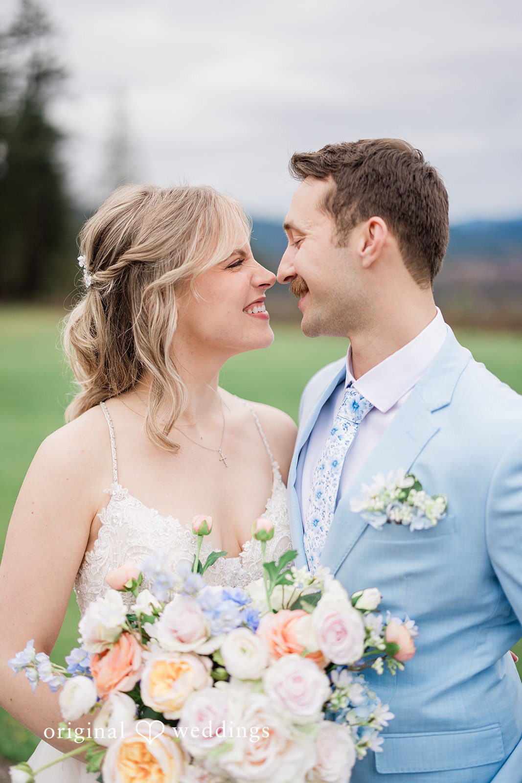 Aubrey + Casey The bride and groom smile lovingly at each other while holding a beautiful bouquet.