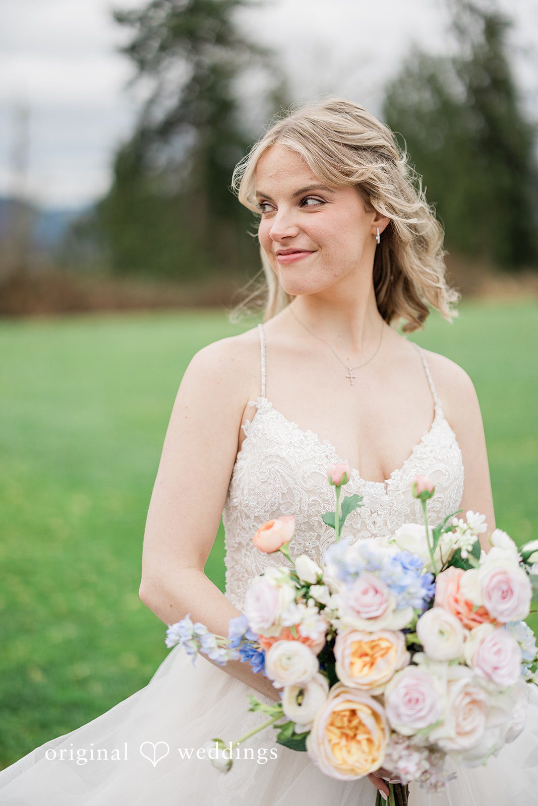 Aubrey + Casey The bride stands outdoors holding her bouquet, looking serene and happy.