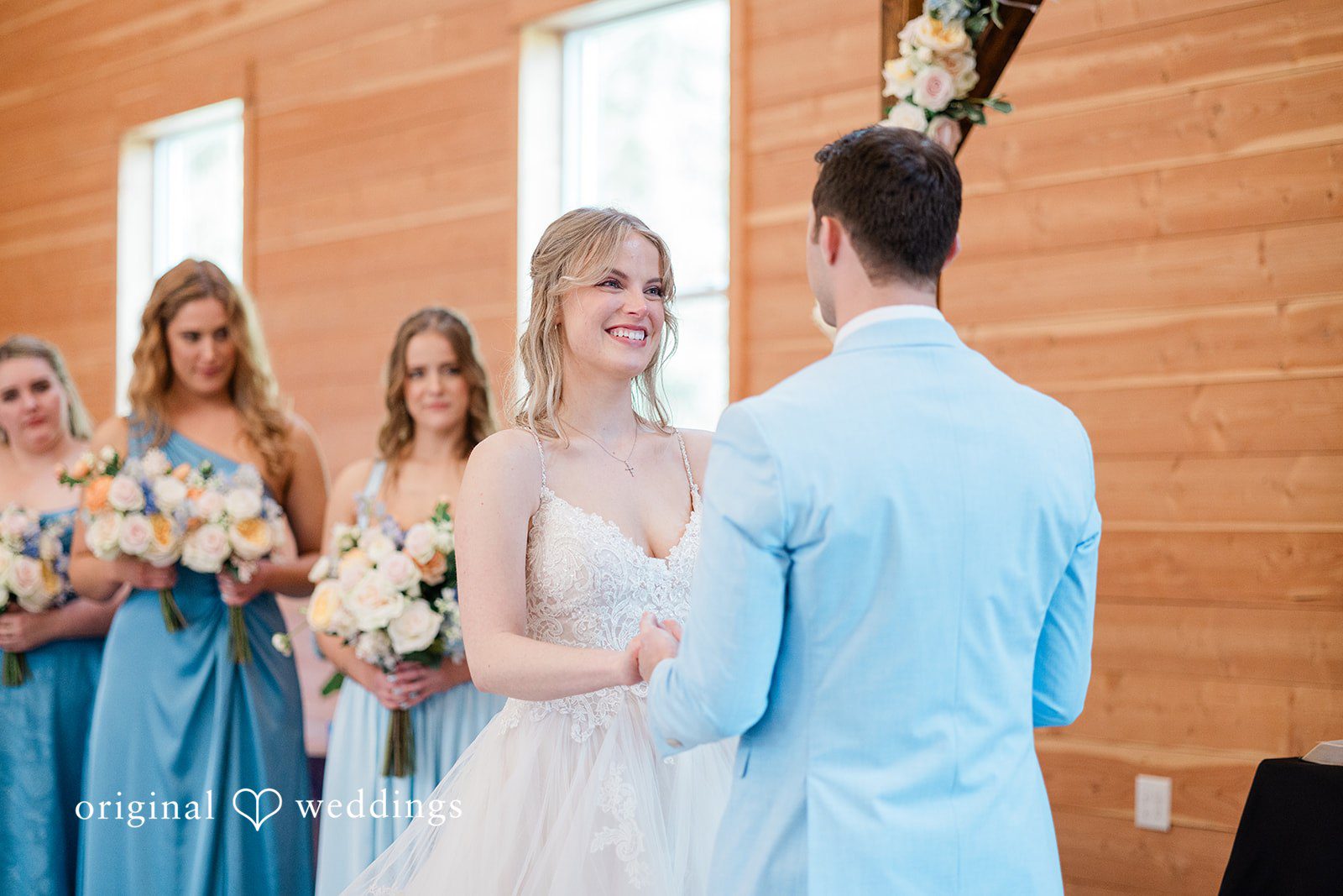Aubrey + Casey The bride smiles brightly while holding hands with the groom during the ceremony.