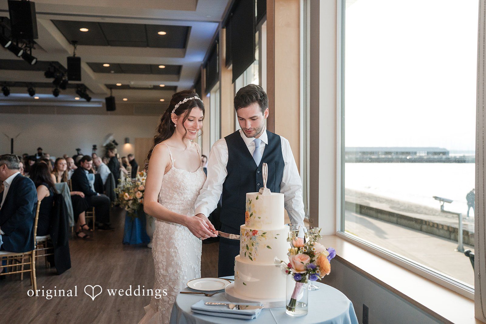 Kelsey + Jensen Seattle Wedding Photographer capturing couple cutting wedding cake at Edmonds Waterfront Center by Original Weddings
