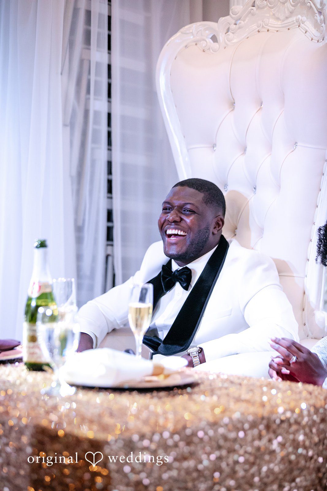 Whitchyna + Kevin Groom sitting on a chair smiling during wedding reception