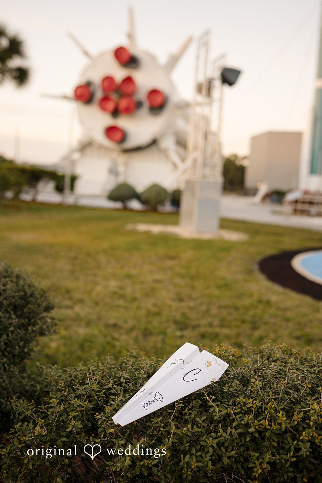 Wedding program cards placed on greenery at Kennedy Space Center captured by Orlando wedding photographer from Original wedding