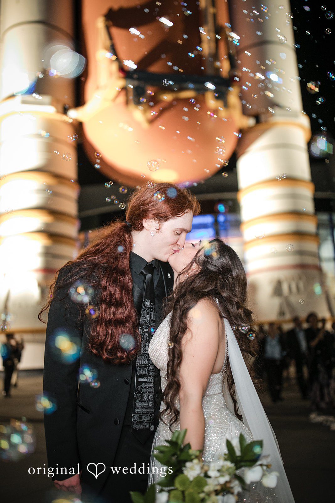 Romantic moment of bride and groom kissing under falling bubbles