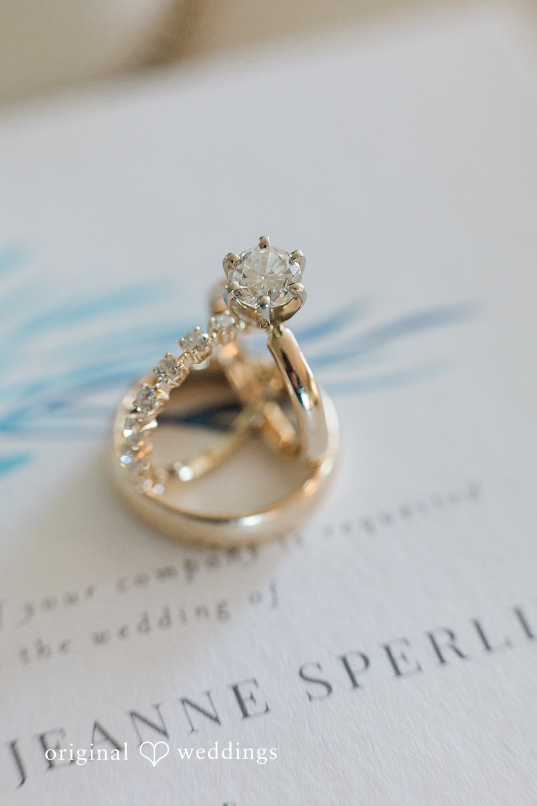 Ethan + Sydney Rings placed on wedding invitation.