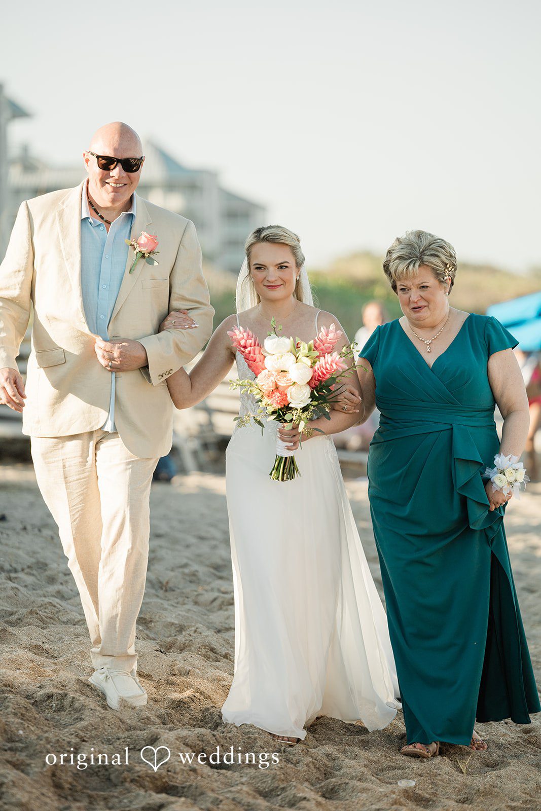 Ethan + Sydney Bride walking on beach with family holding bouquet at Marriott Hutchinson Island Beach Resort.