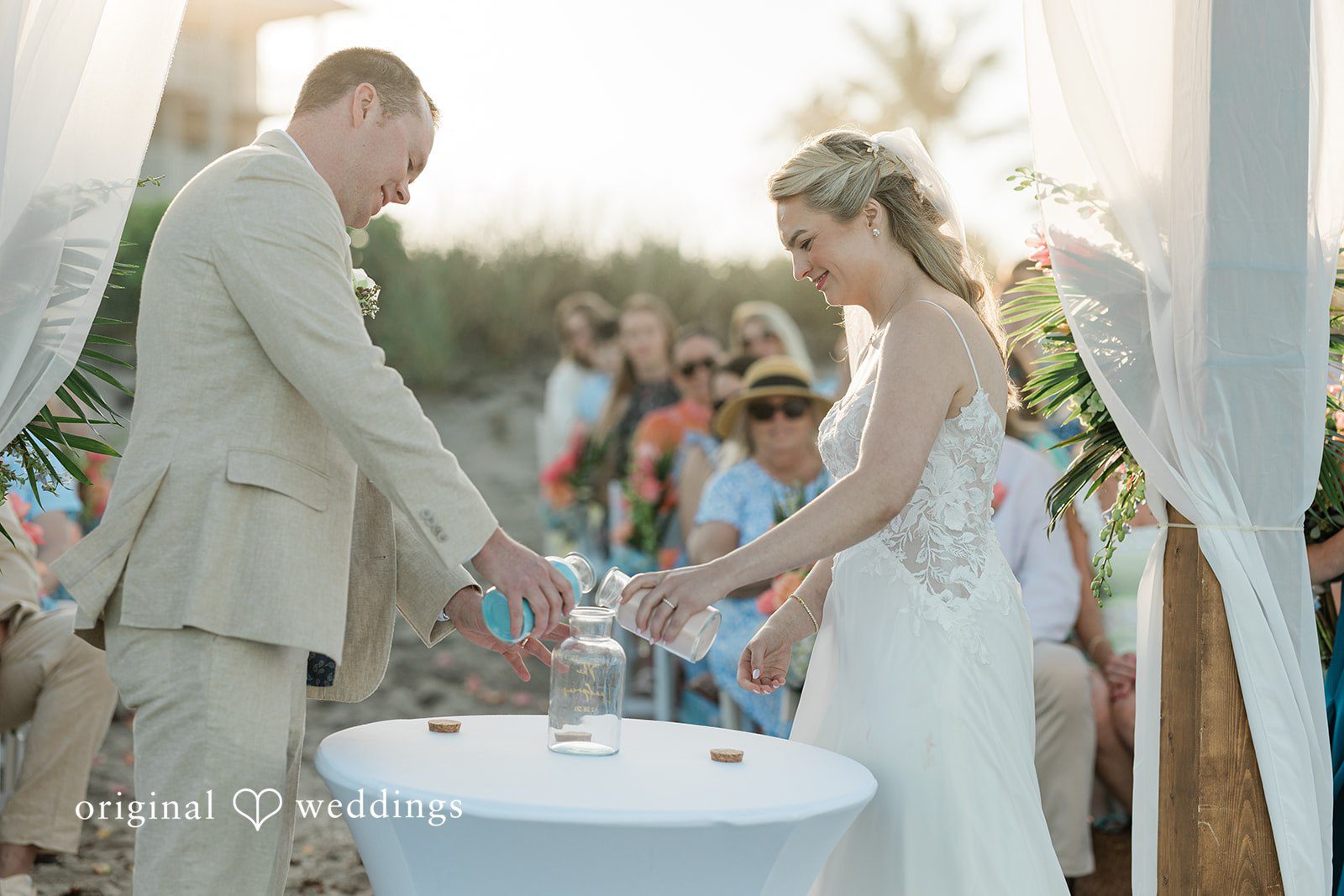Ethan + Sydney Bride and groom pouring sand into a glass at an outdoor wedding ceremony.