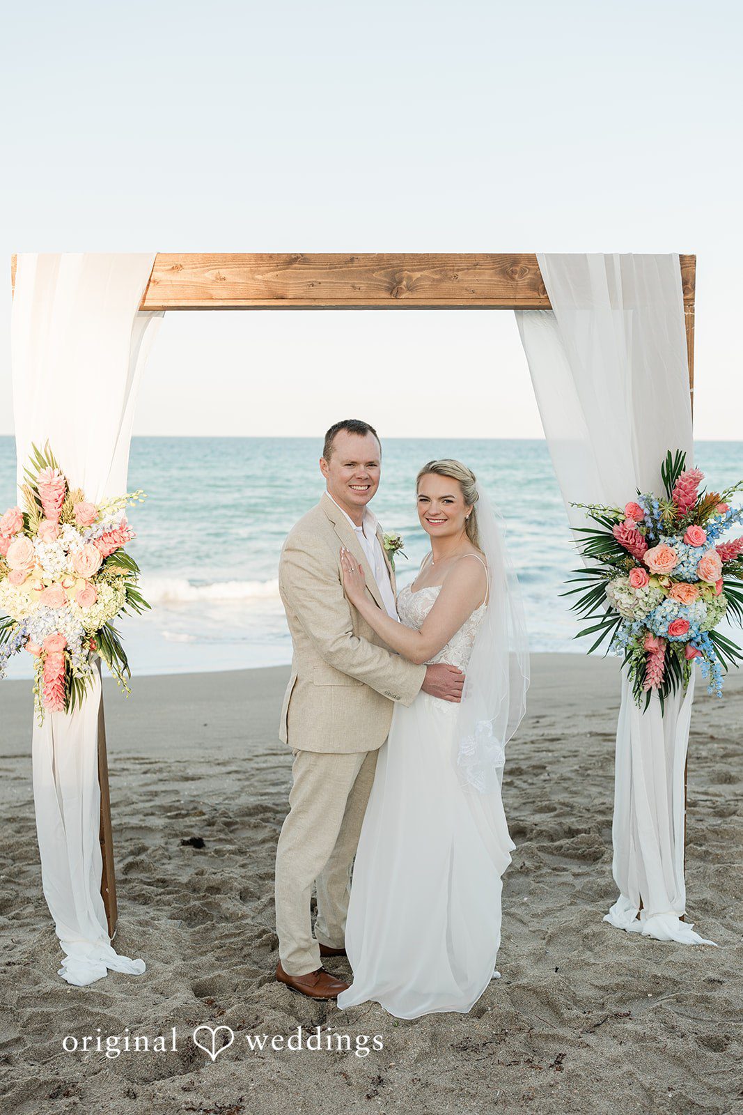 Ethan + Sydney Couple posing under wooden beach arch at Marriott Hutchinson Island Beach Resort.