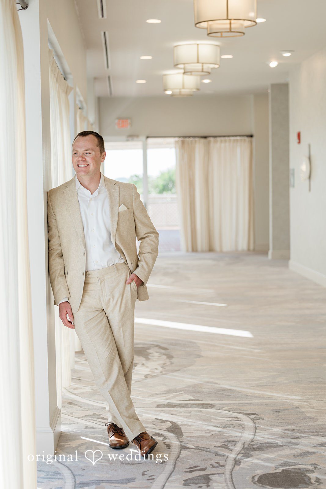 Ethan + Sydney Groom posing in light suit indoors.