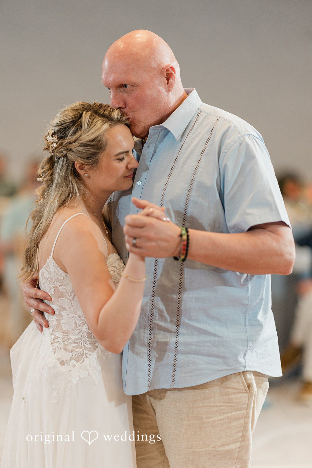 Ethan + Sydney Bride in a white wedding dress dancing with a man , holding hands and embracing closely.