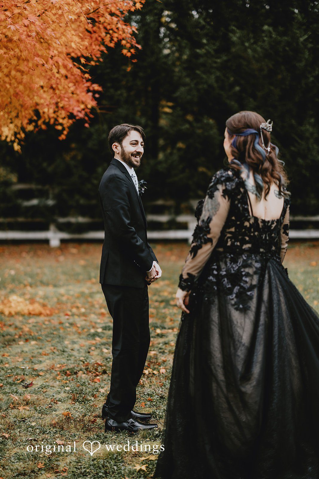 Two people walking along a gravel path are framed by trees and open space.
