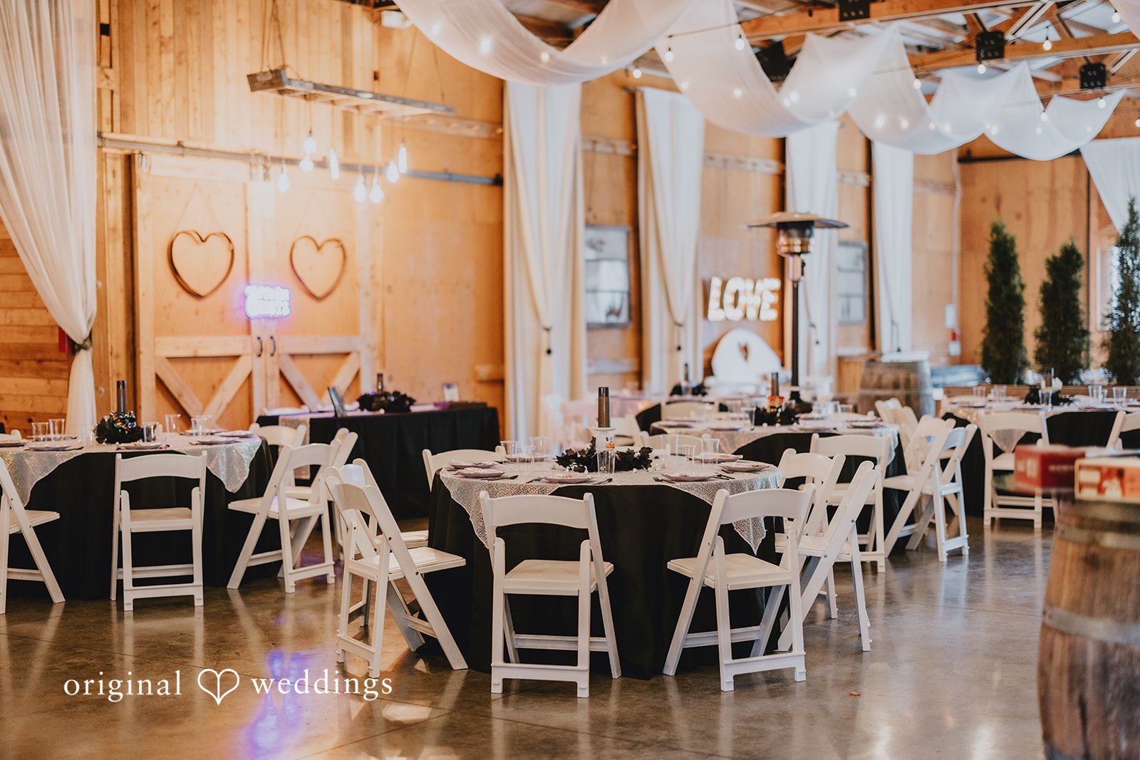A prepared reception space with long tables and white chairs showcases the rustic elegance of the venue.